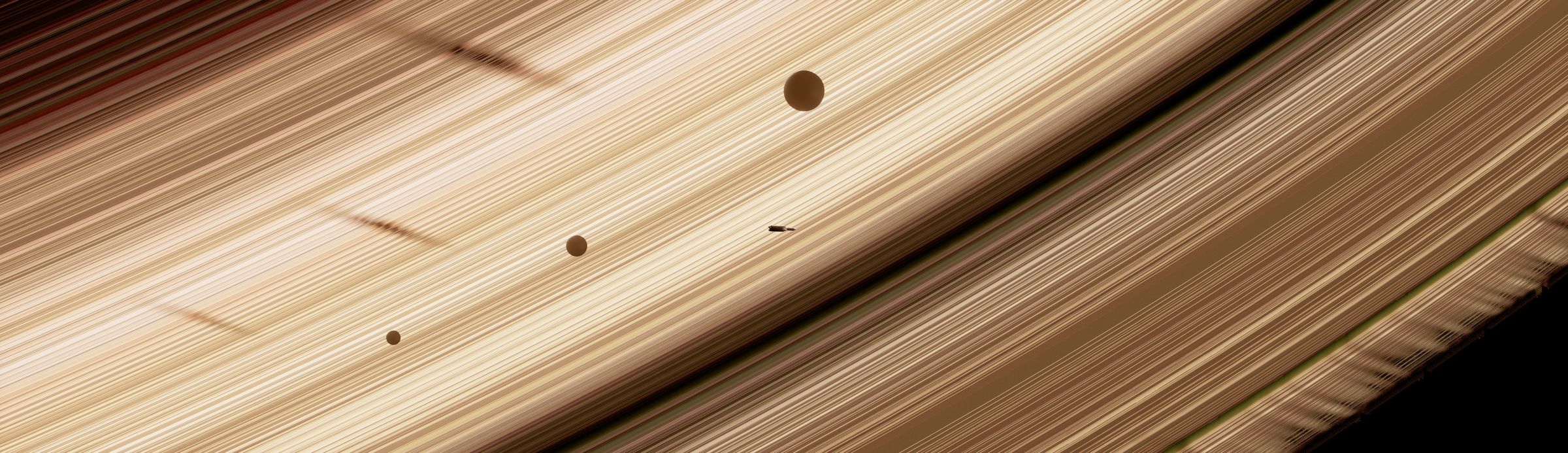 Close over Saturn's rings, the rocket flying among small moons and their shadows